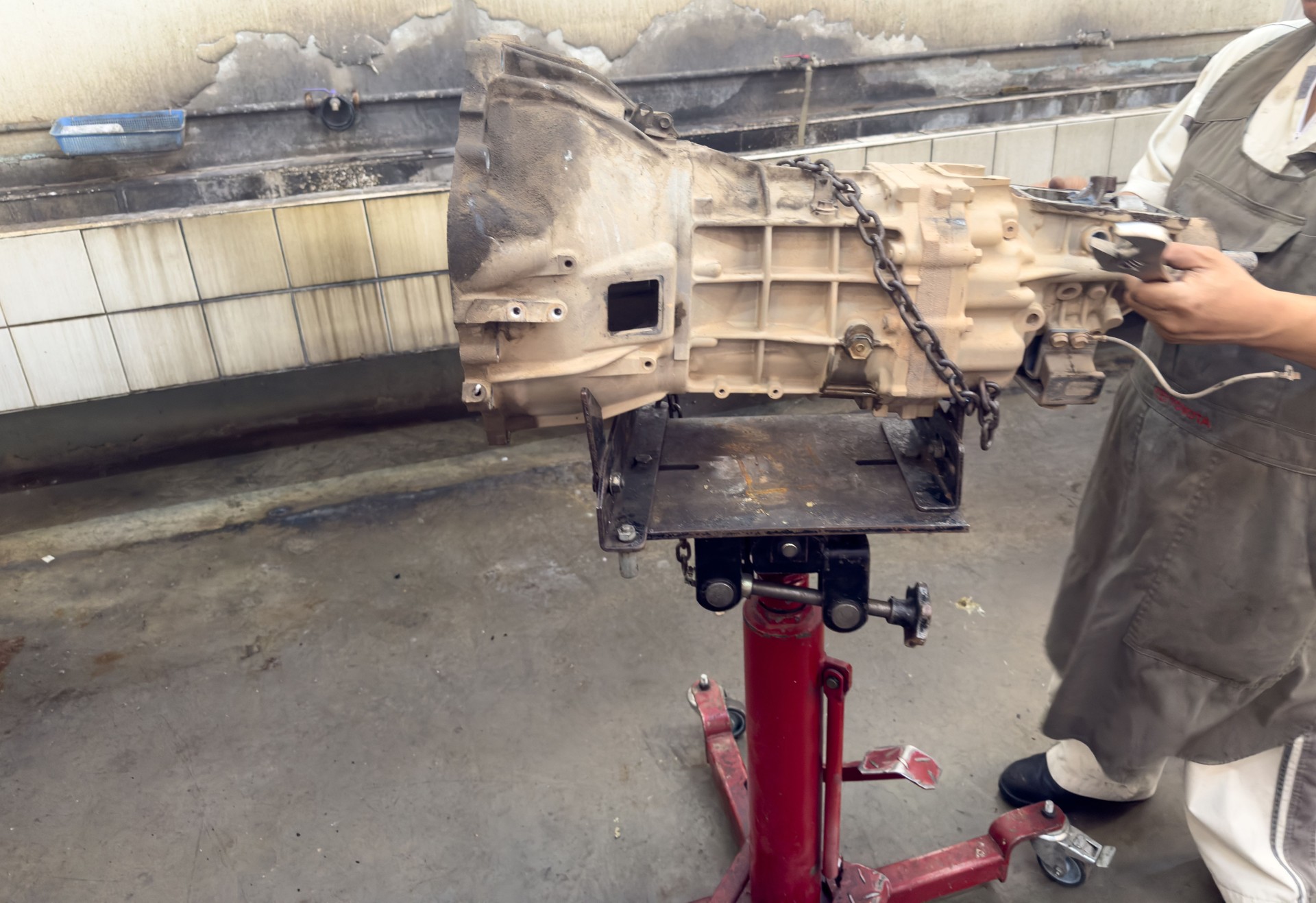 A team of expert technicians is performing maintenance on a complex car transmission system.